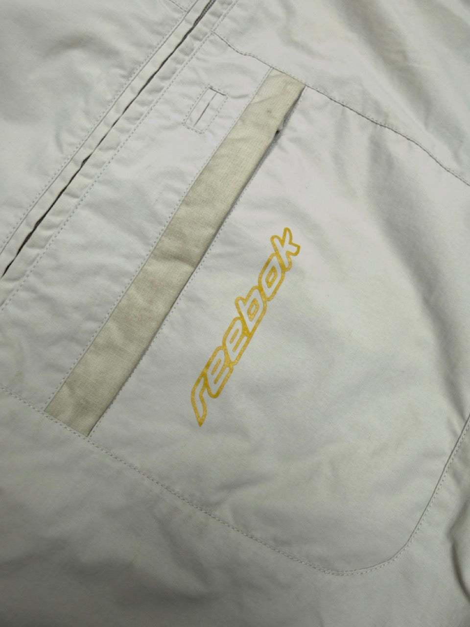 Reebok Windbreaker creme goldener Reebok Schriftzug Detail
