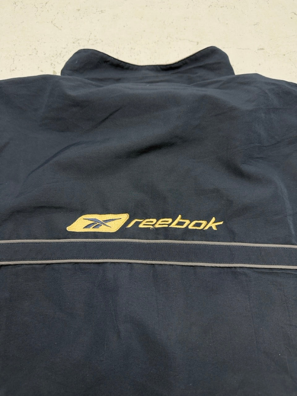 Reebok Jacke navy gold Logo Detail auf dem Rücken