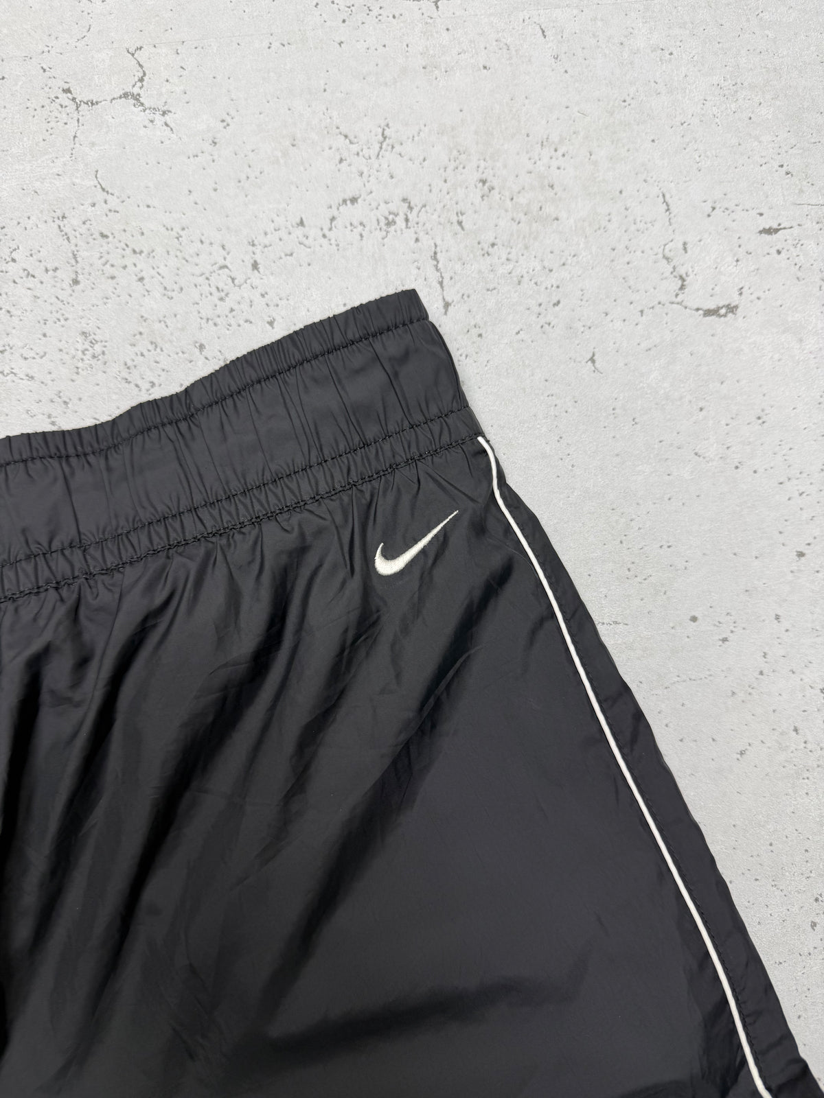 Nike Vintage Trackpants in Schwarz mit weißer Paspel, Größe M, Swoosh-Logo Nahaufnahme