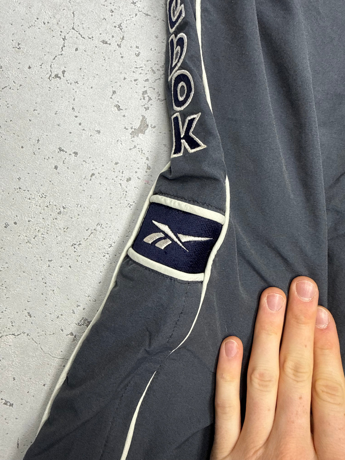 Reebok Vintage Trackpants in Anthrazit, Detailaufnahme des Vector Patches in Navy